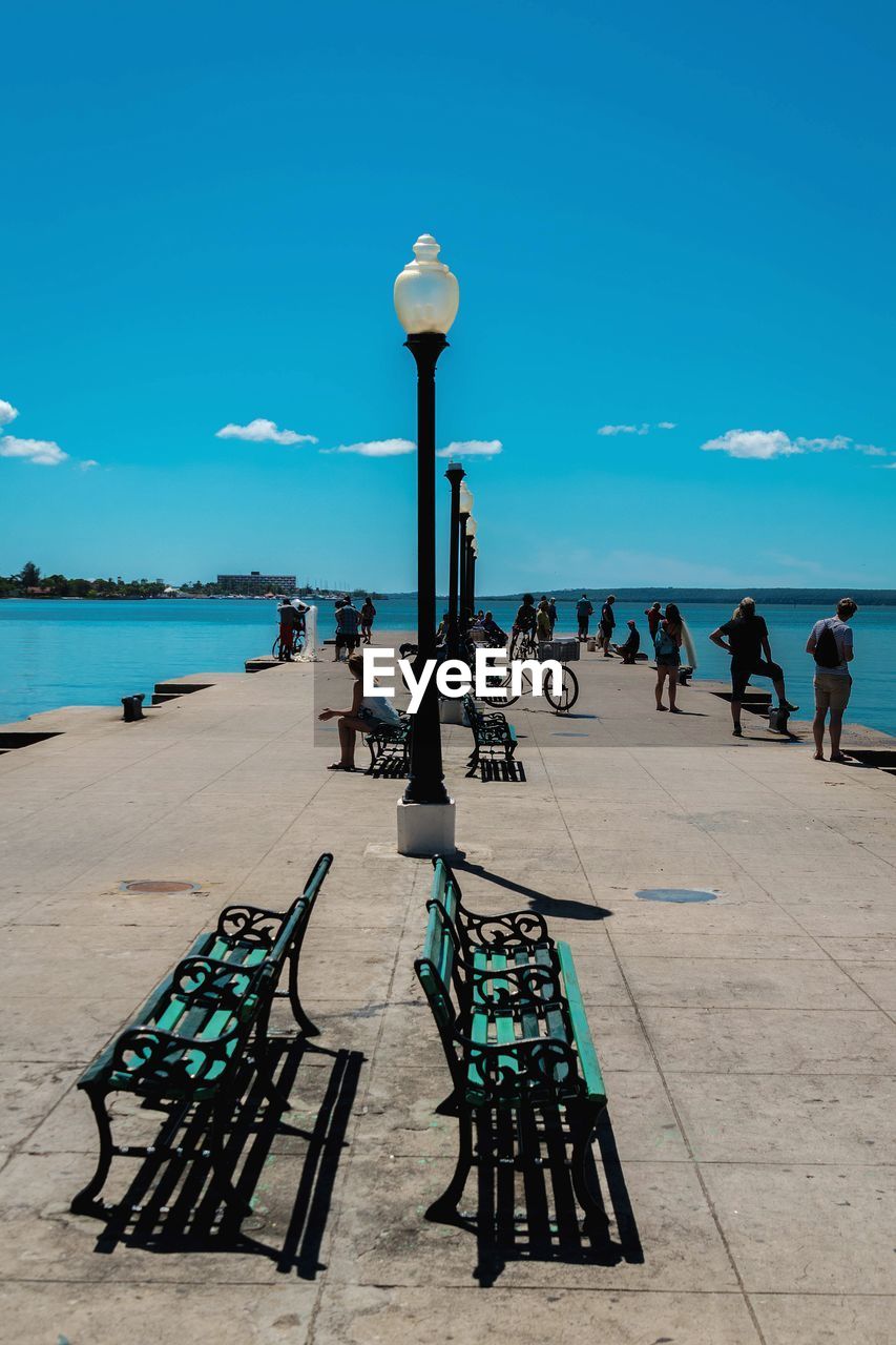 People on pier against blue sky