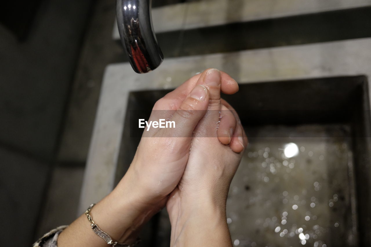 Cropped image of woman washing hands in sink at home