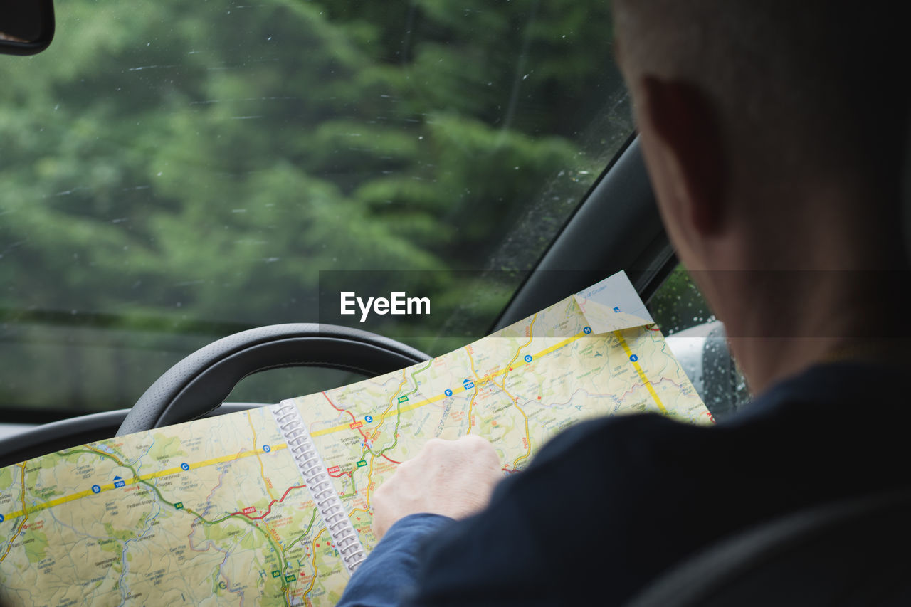 Rear view of man with map in car