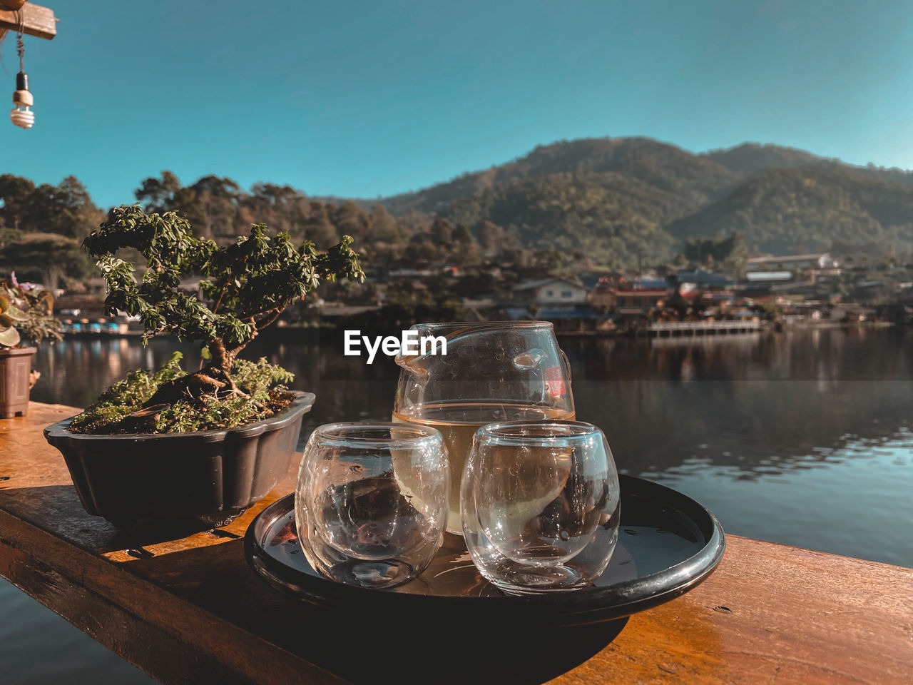 Drinking glass on table by lake against sky