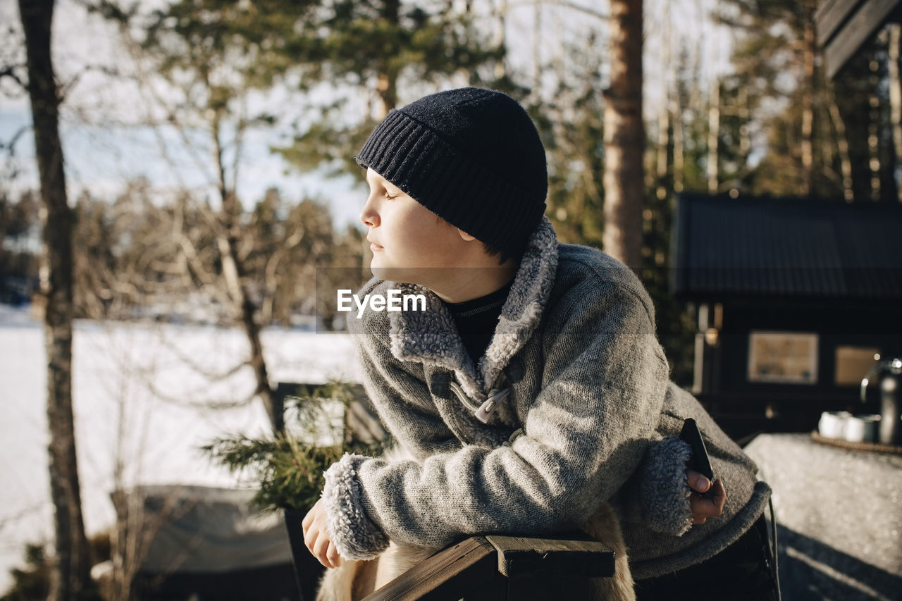 Boy with eyes closed enjoying sunlight during winter