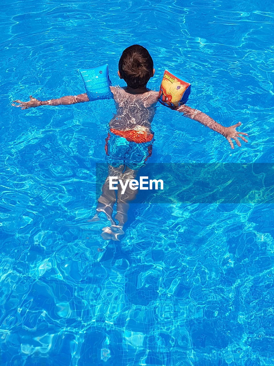 HIGH ANGLE VIEW OF BOY ON SWIMMING POOL
