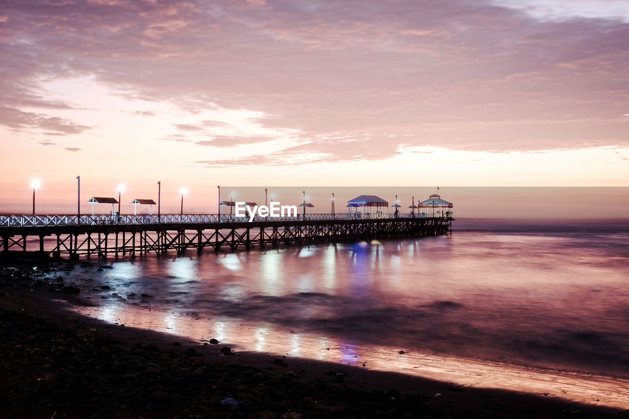 Pier over sea against sky at sunset