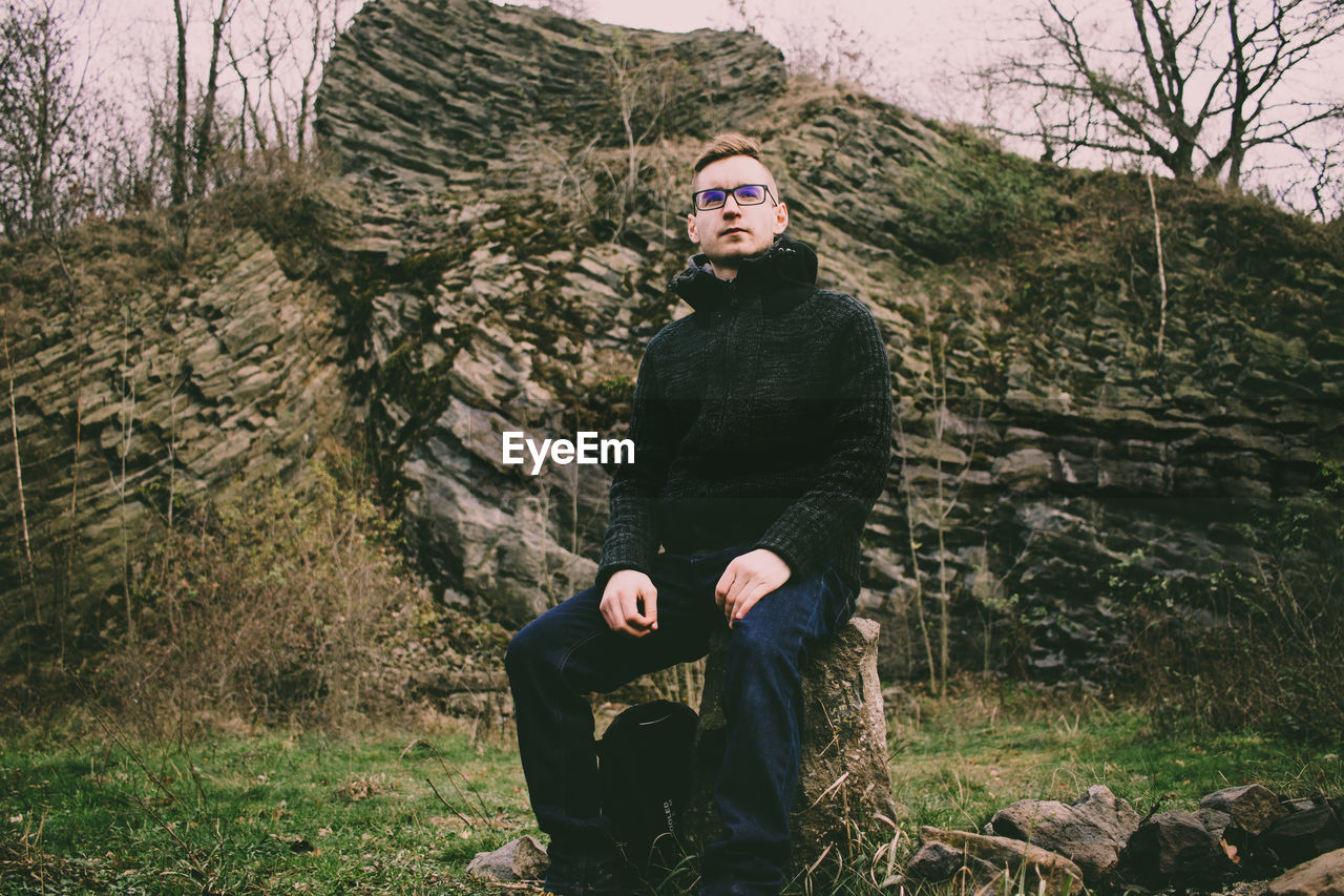 Man sitting on tree stump in forest