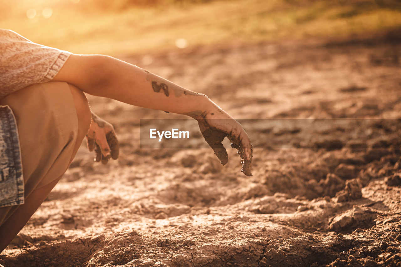 Midsection of person crouching on sand