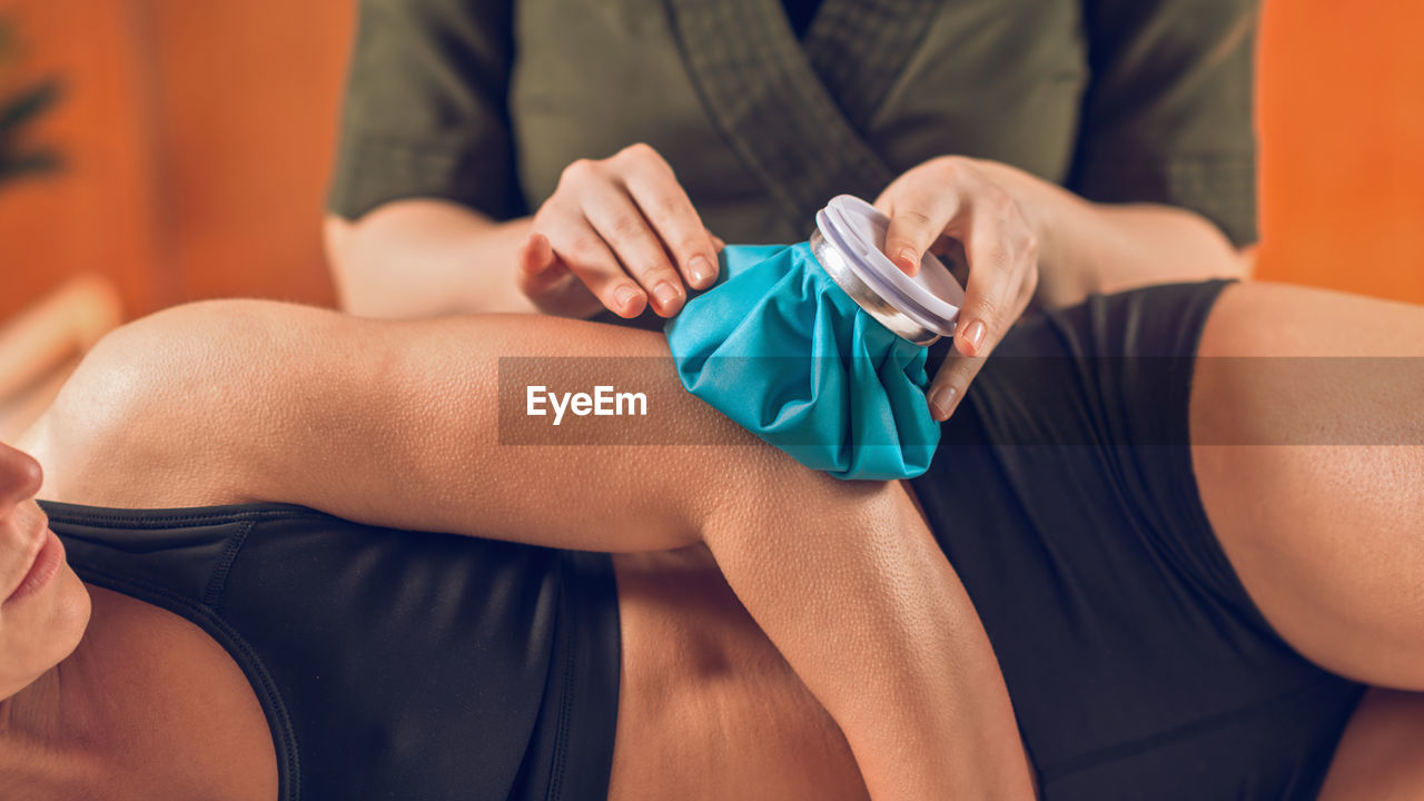 Midsection of woman holding ice pack on athlete elbow