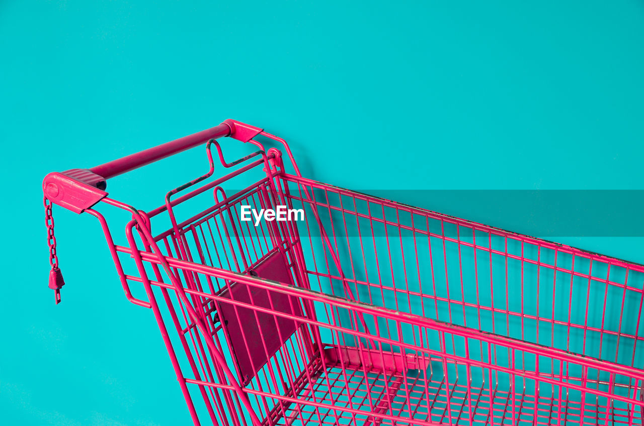 Pink shopping cart against colored background