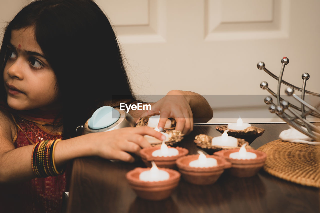 Smiling girl burning diya at home