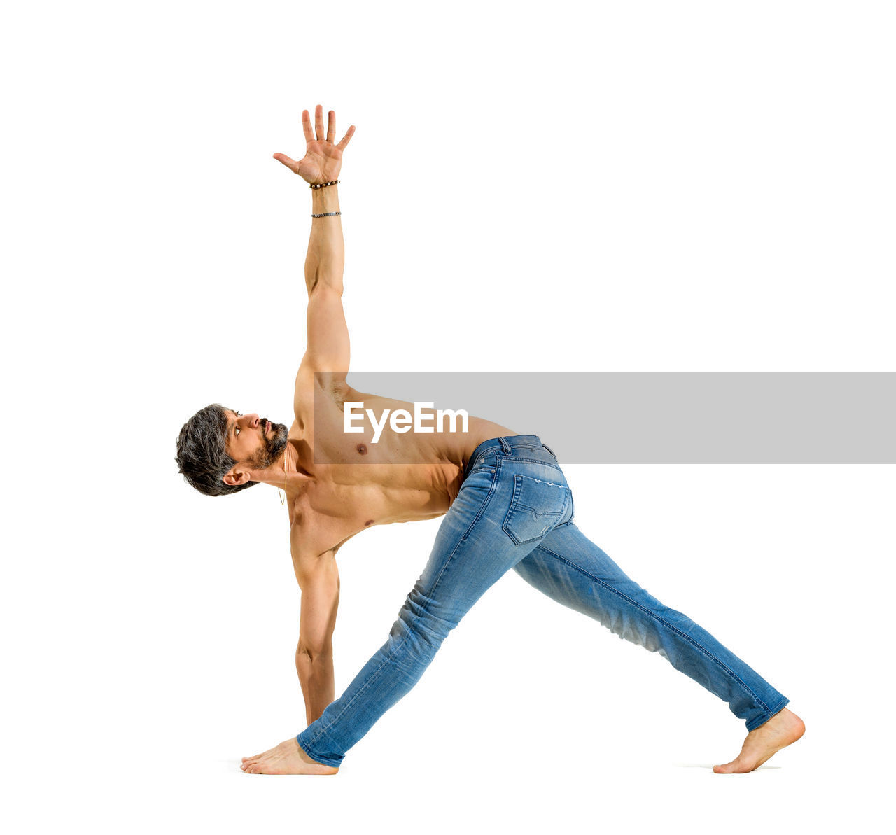 LOW ANGLE VIEW OF SHIRTLESS MAN WITH ARMS RAISED