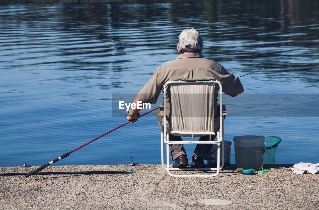 Rear view of man fishing in lake