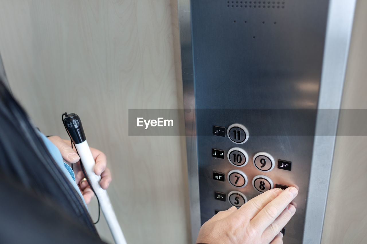 Person with white cane using elevator