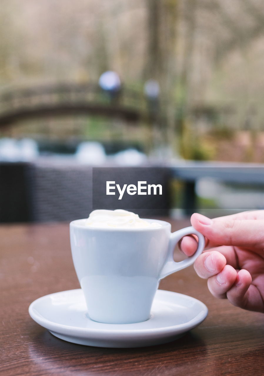 CLOSE-UP OF HAND HOLDING COFFEE