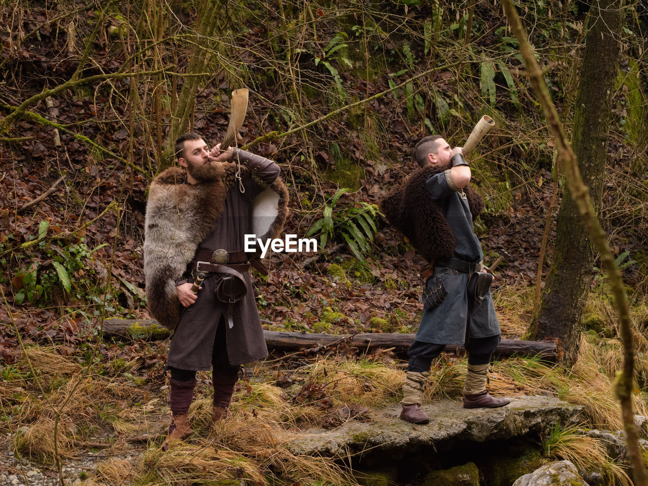 Men wearing costume standing on rock in forest