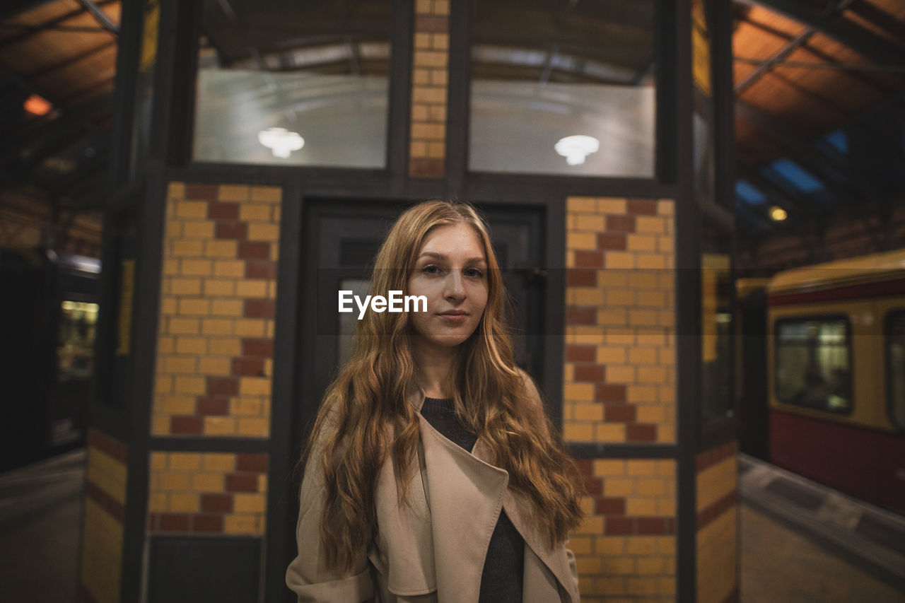 Portrait of young woman standing at subway station