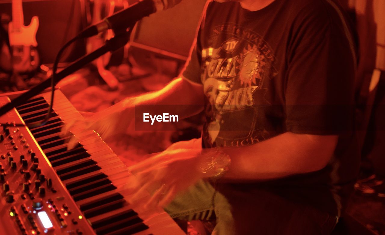 Cropped view of young man playing keyboard in band