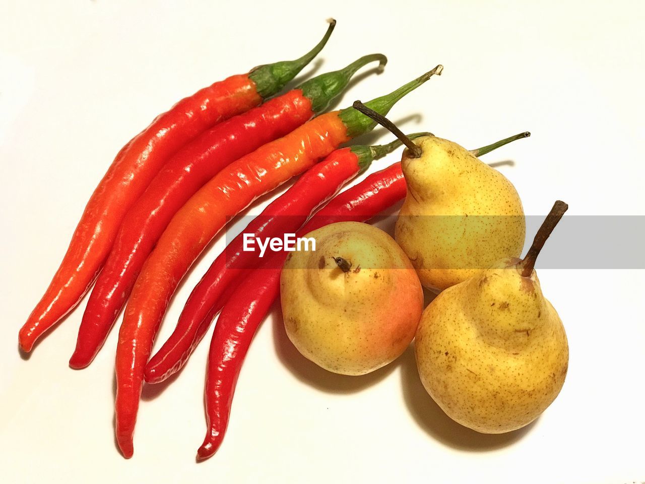 CLOSE-UP OF FRESH RED CHILI PEPPERS AGAINST WHITE BACKGROUND