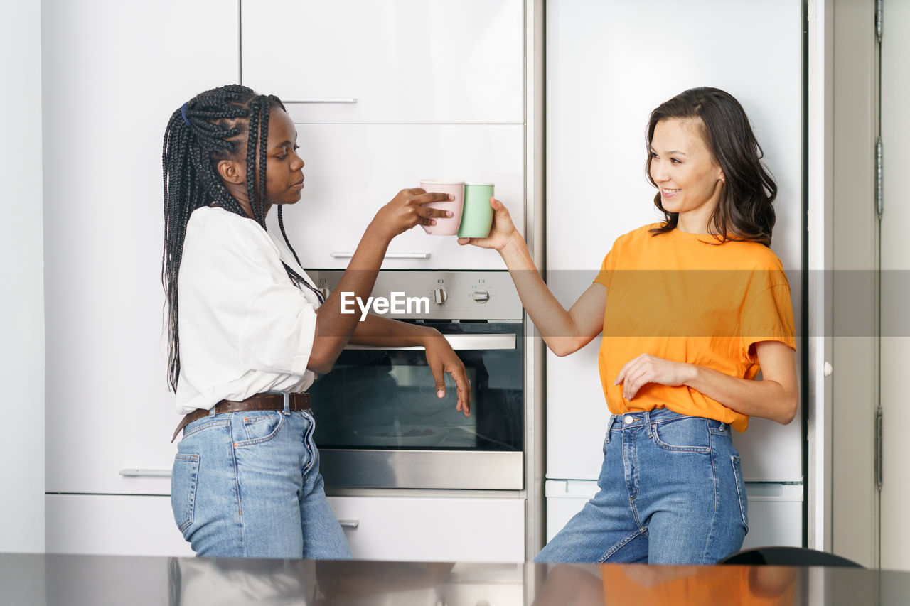 Young women talking while standing at kitchen
