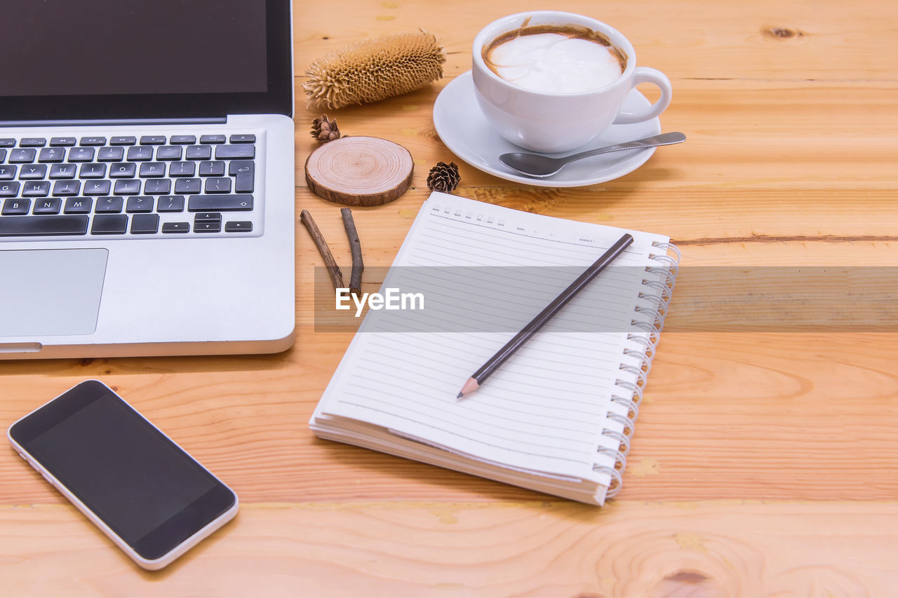 High angle view of mobile phone with coffee on wooden table