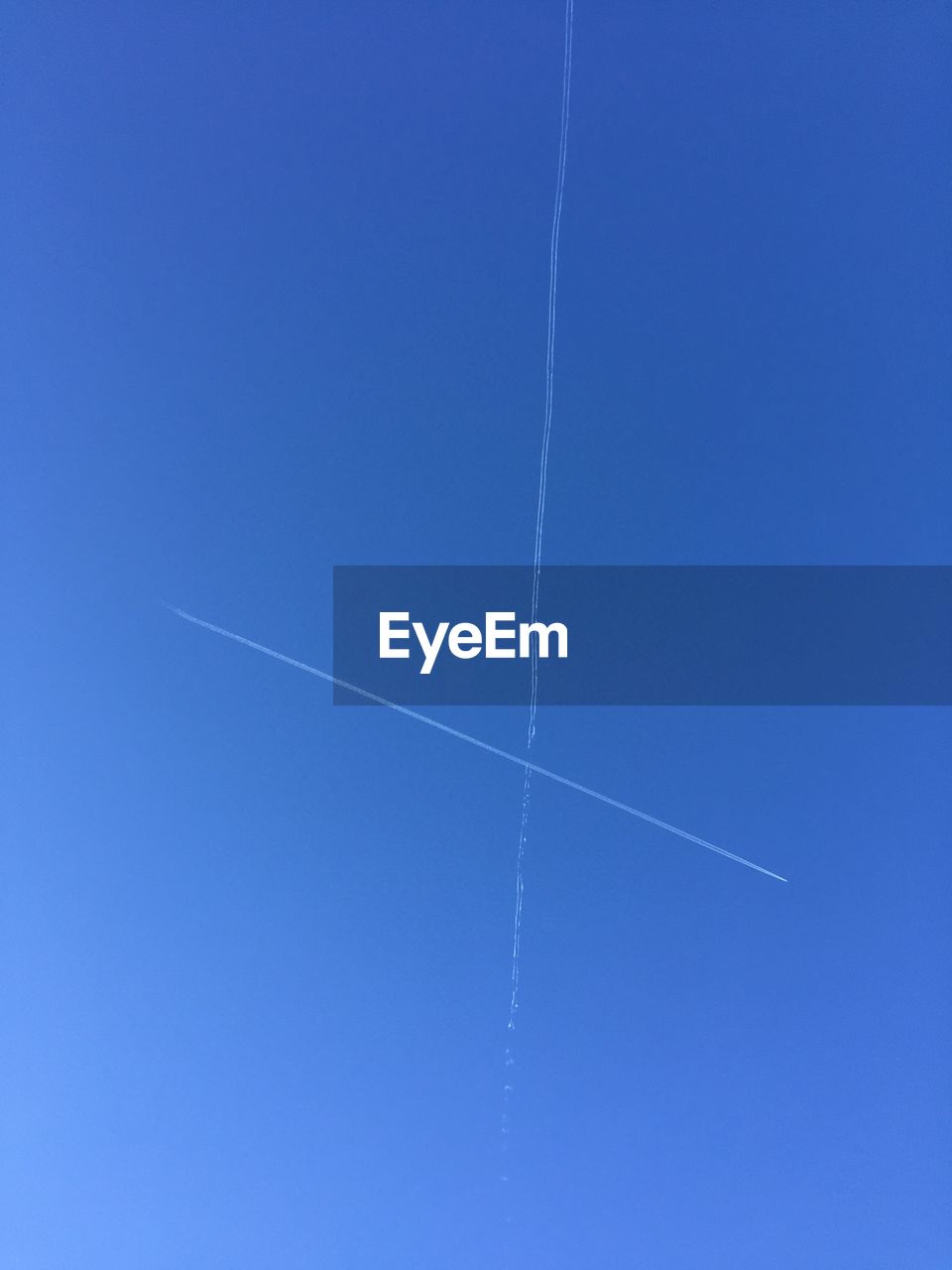 Low angle view of vapor trails against clear blue sky