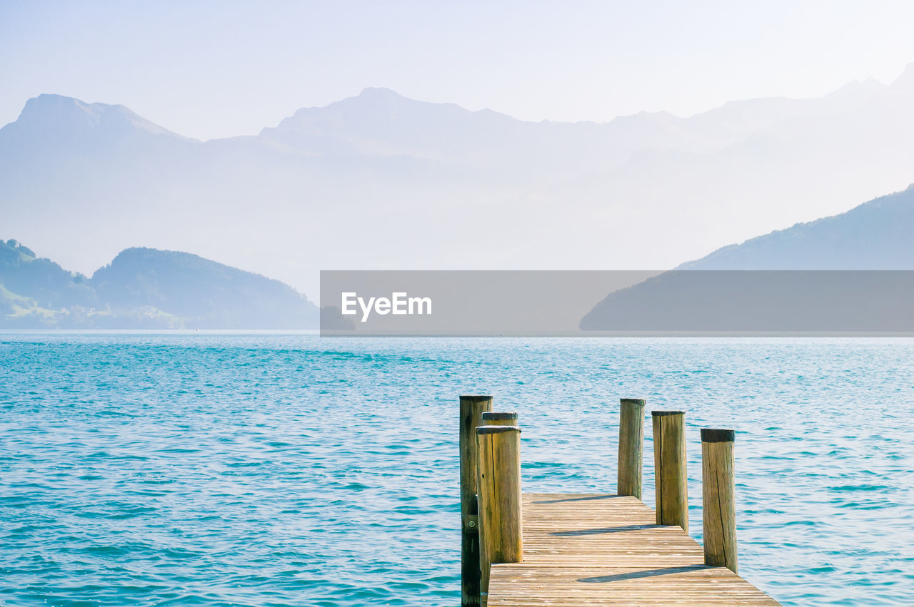 PIER OVER SEA AGAINST MOUNTAINS