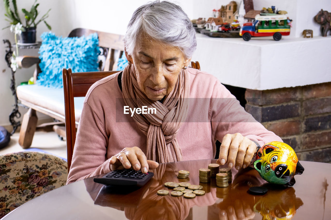 Senior woman counting coins on table