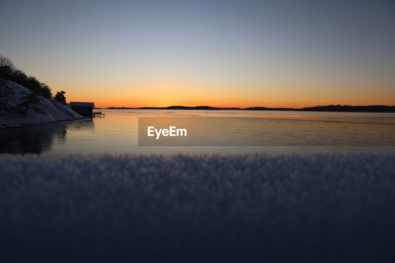 water, sky, reflection, morning, scenics - nature, horizon, beauty in nature, tranquility, dawn, nature, sunrise, tranquil scene, sea, land, no people, landscape, environment, sunlight, beach, idyllic, shore, outdoors, cloud, ocean, travel destinations, clear sky, non-urban scene, copy space, coast, architecture, sun