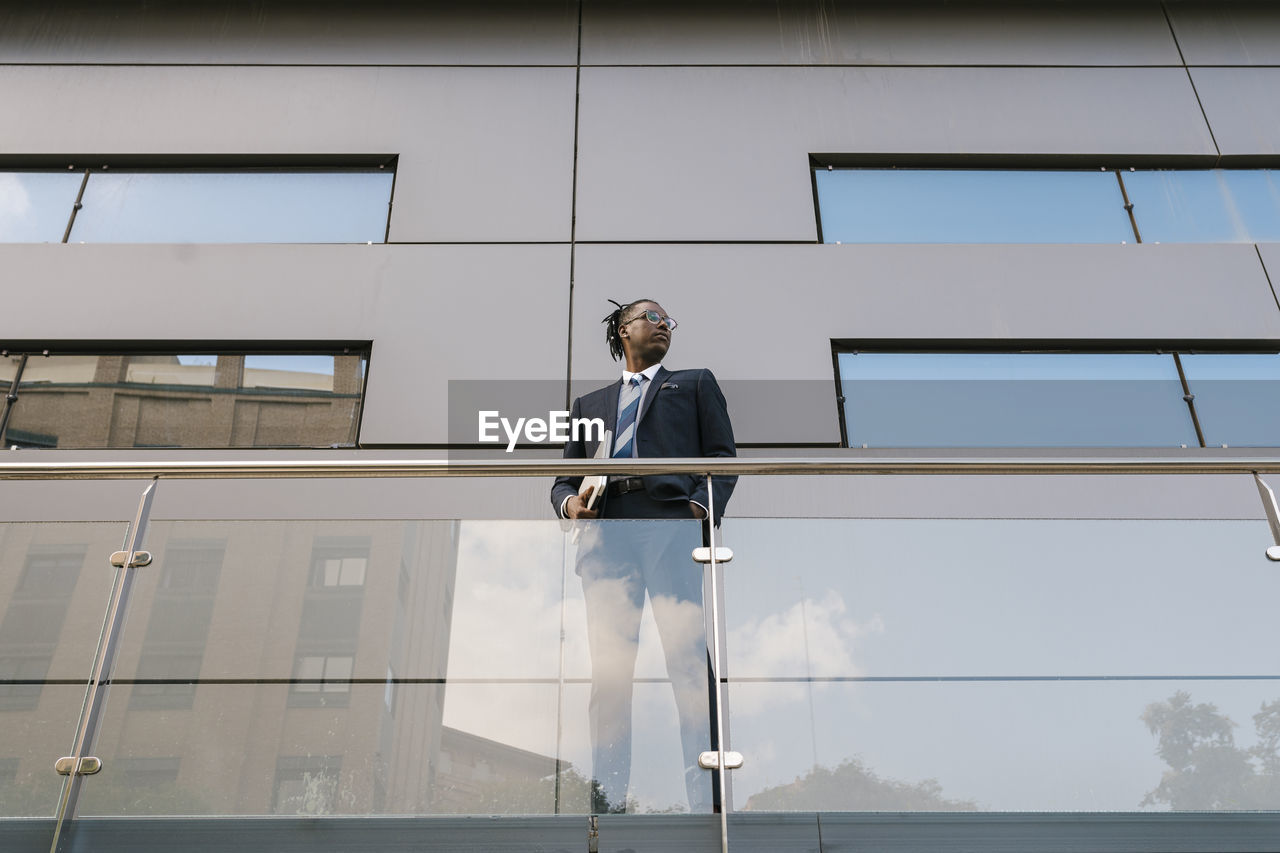 Businessman holding laptop while standing at office building