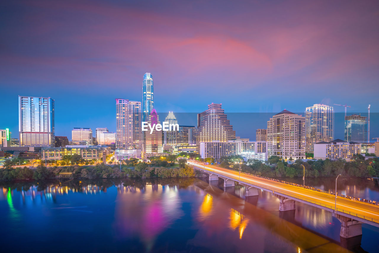 Reflection of illuminated buildings in river against sky