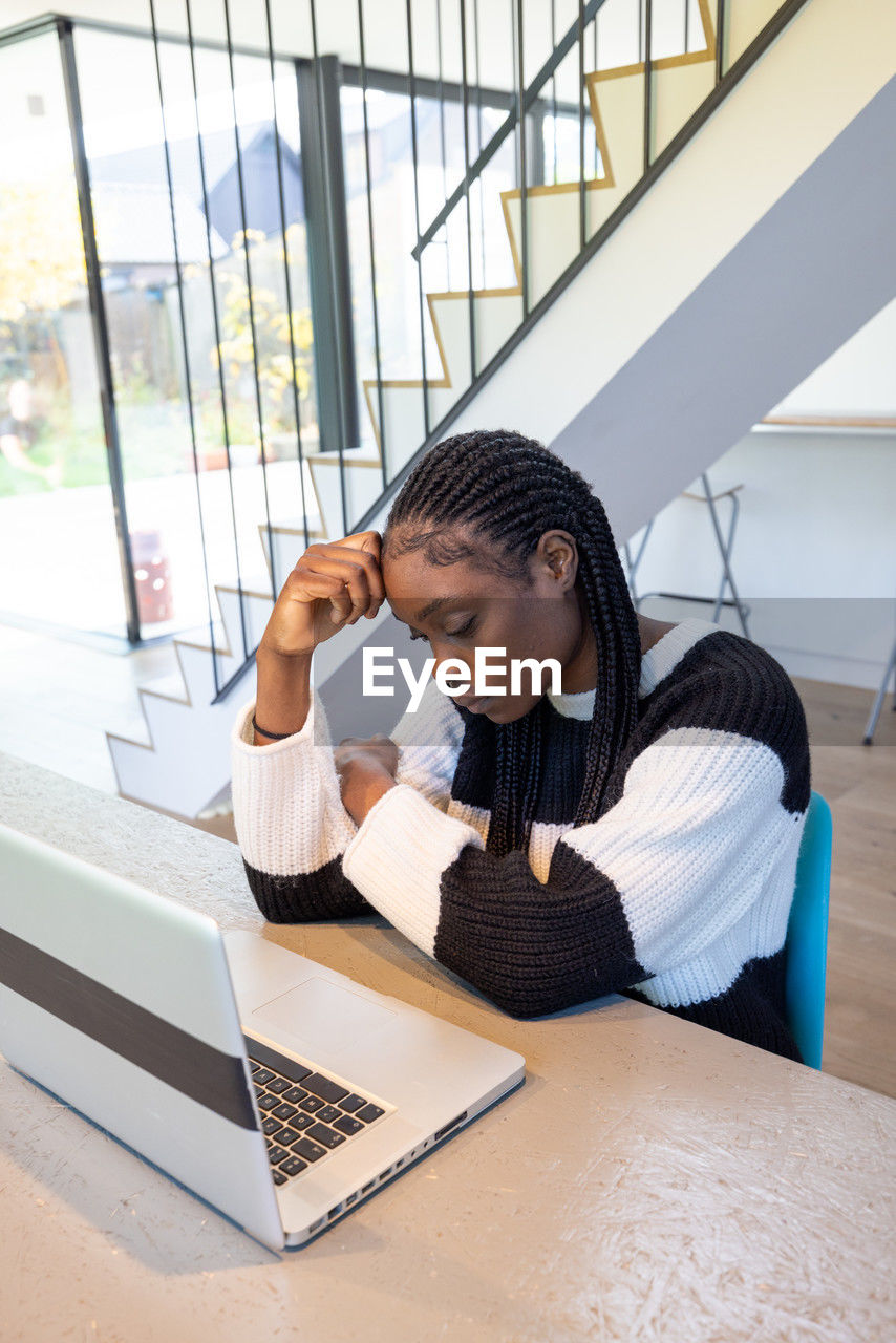 side view of young woman using laptop on table in office