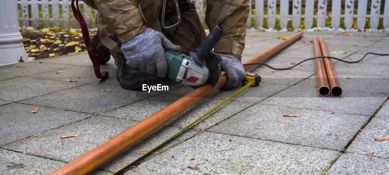 LOW SECTION OF MAN WORKING ON FOOTPATH BY SIDEWALK