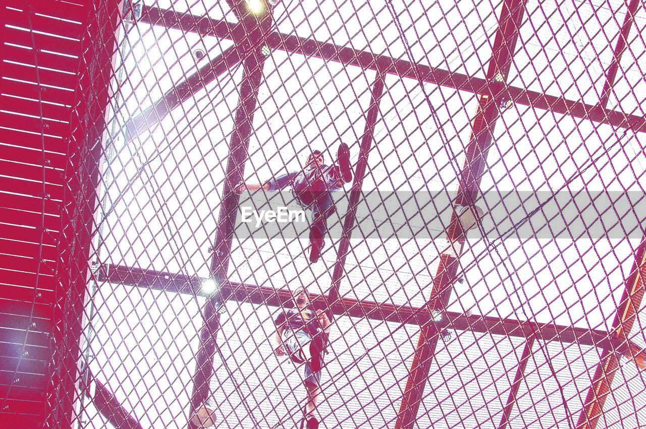 Low angle view of people walking along metal grate overpass