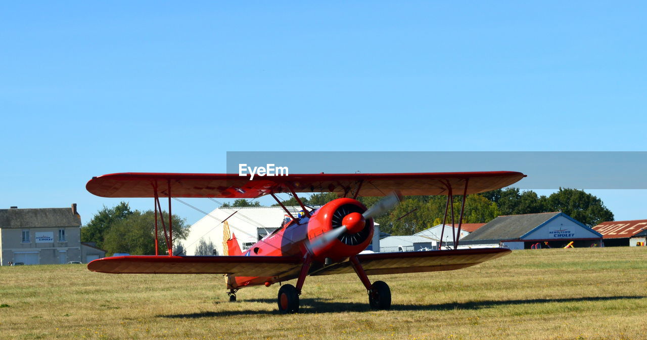 AIRPLANE ON FIELD AGAINST SKY