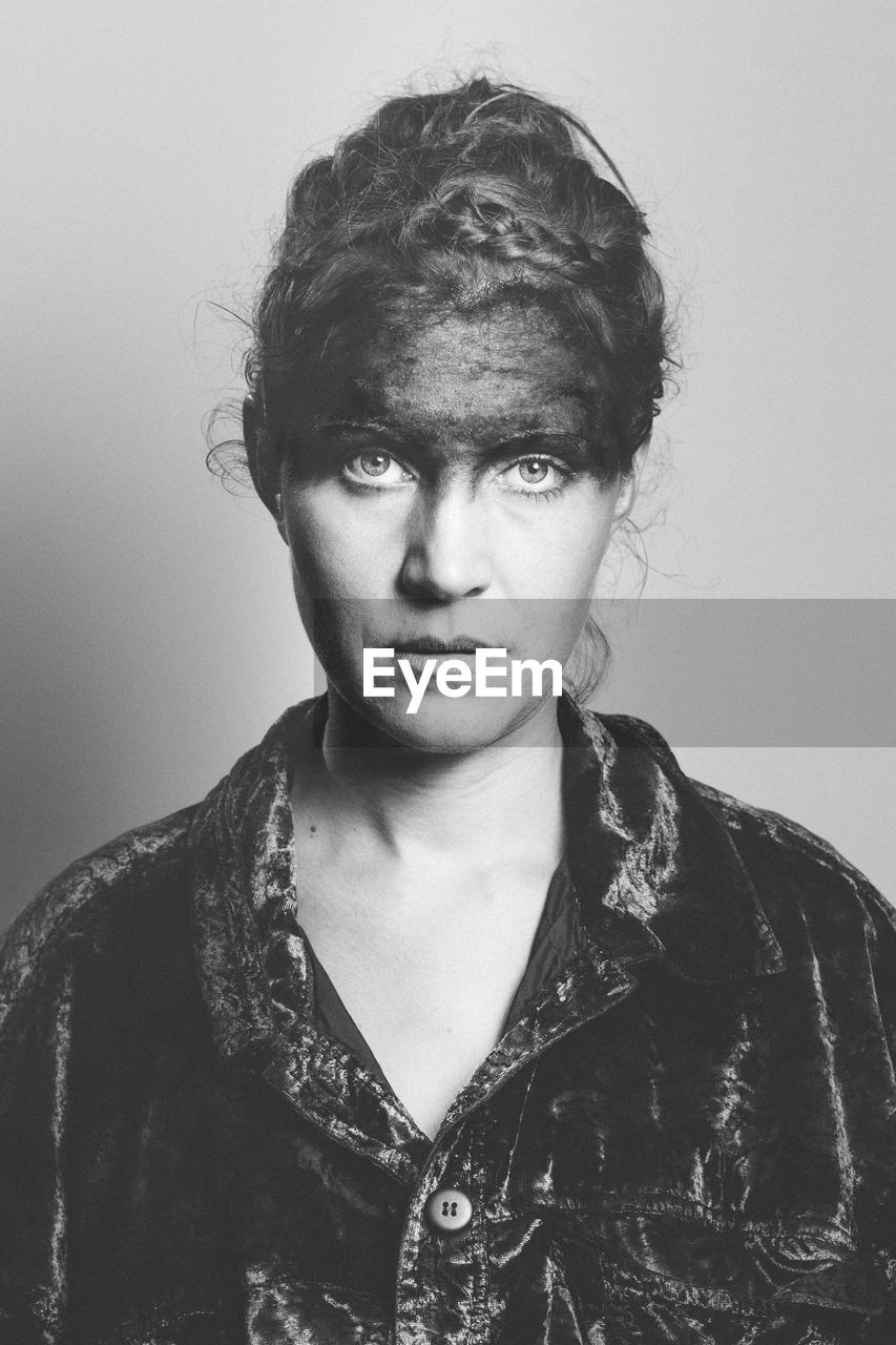 Portrait of woman with face paint against gray background