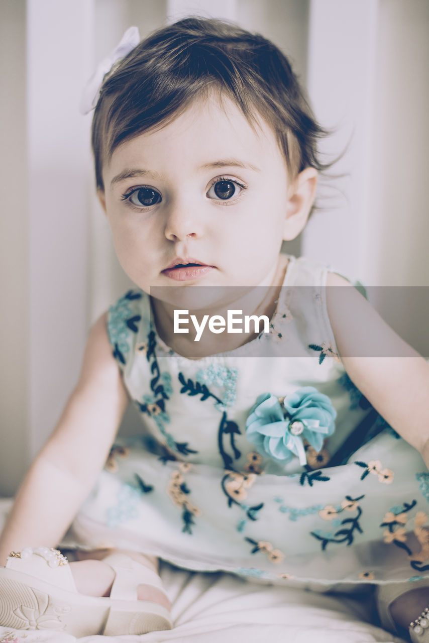 Portrait of cute baby girl sitting at home