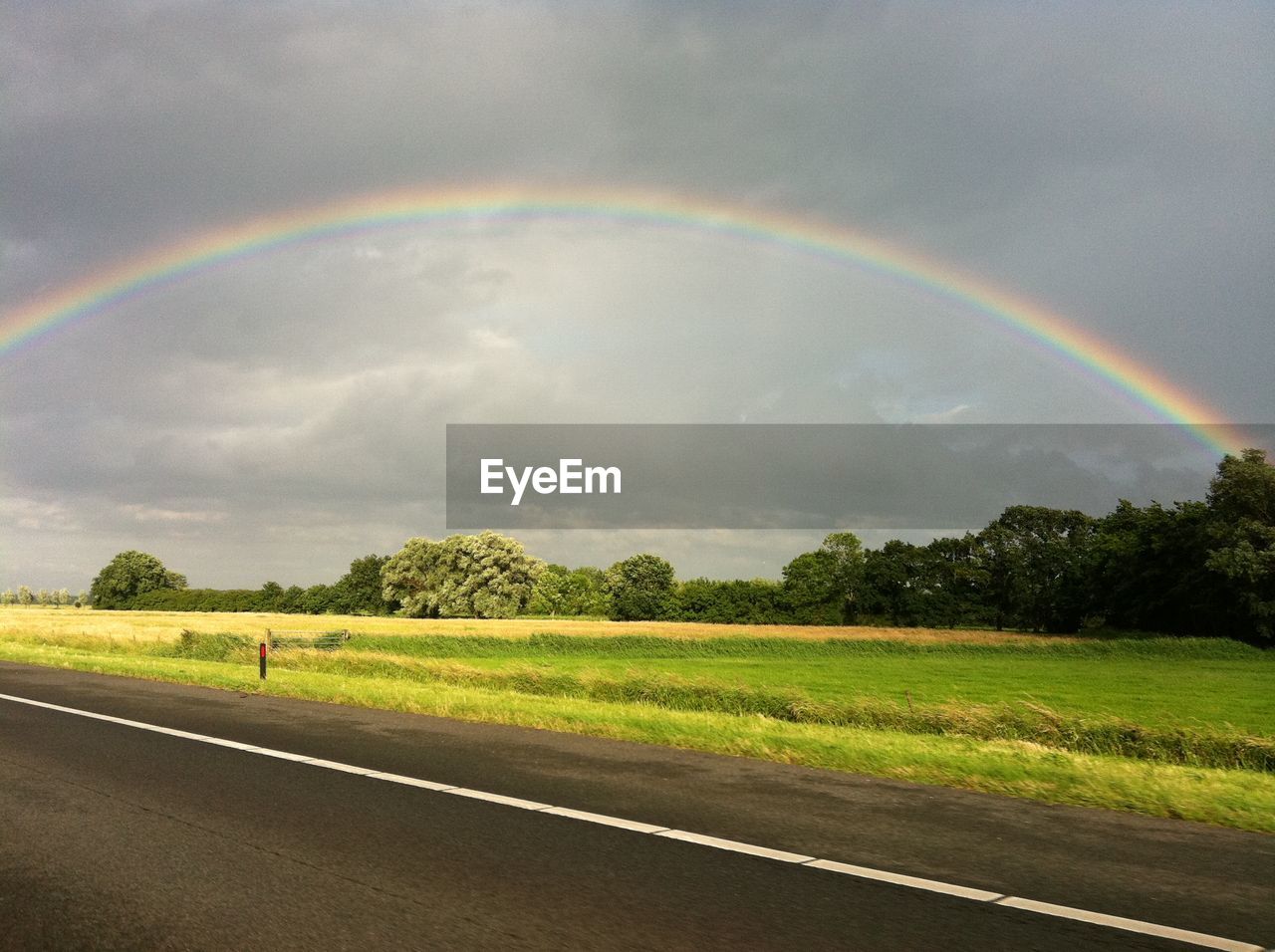 Scenic view of rainbow over field against sky