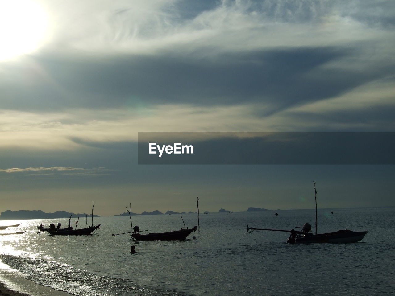 Silhouette boats in sea against sky during sunset