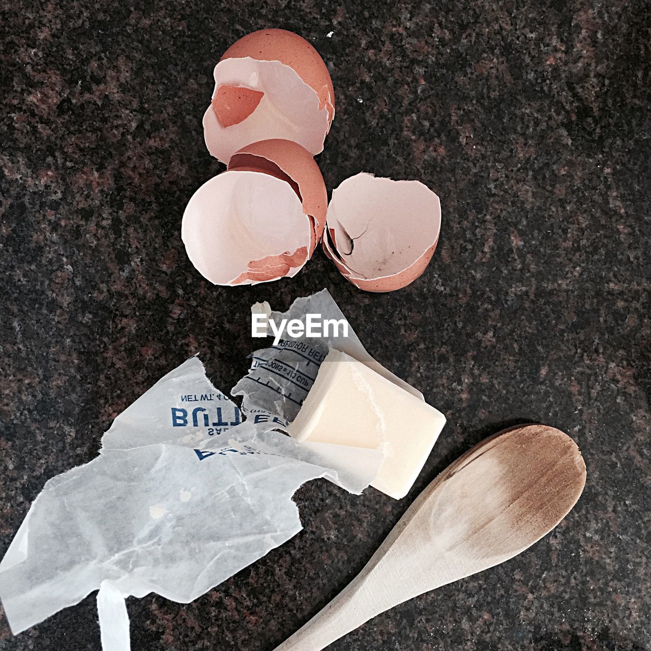 Close-up of broken egg shell with butter and spatula