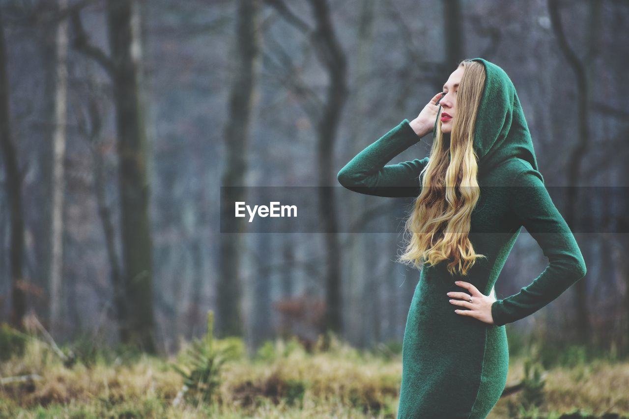 Side view of woman standing in forest