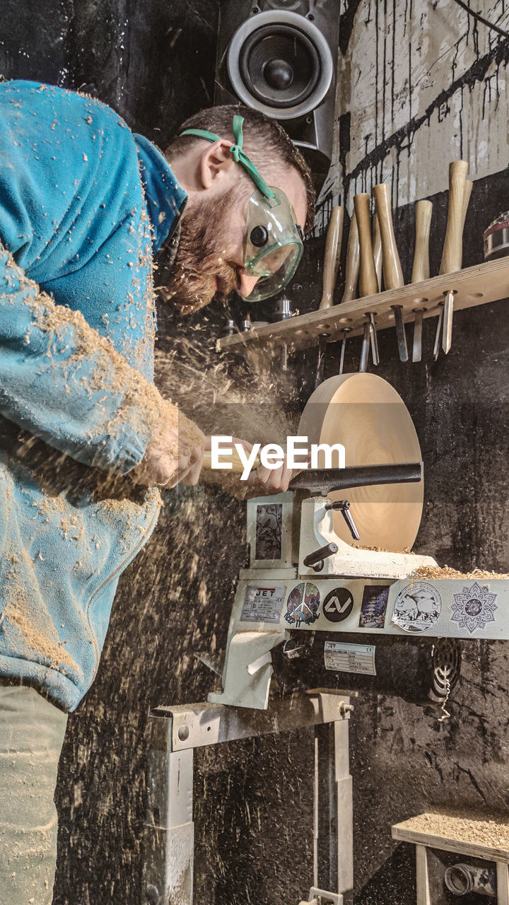 SIDE VIEW OF A MAN WORKING ON STONE