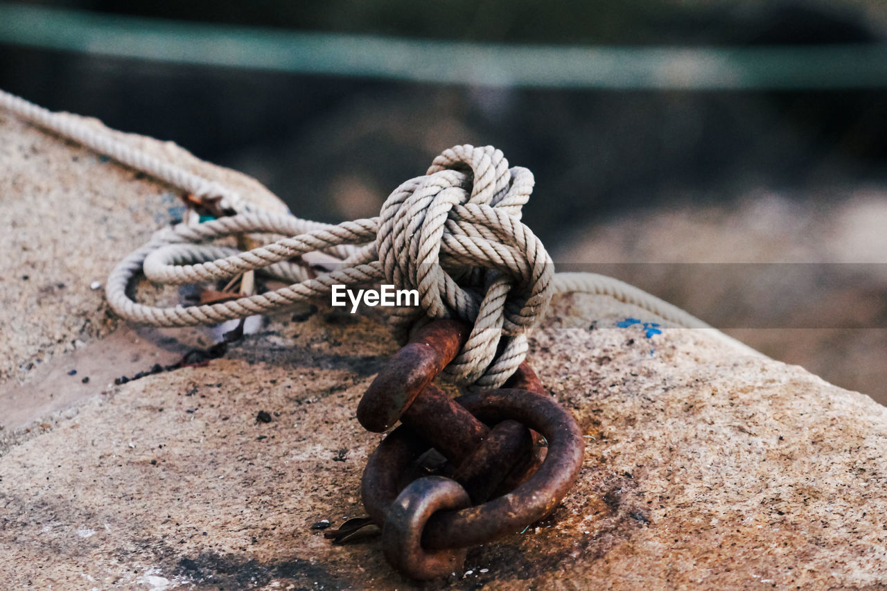 CLOSE-UP OF ROPE TIED UP ON RUSTY METAL