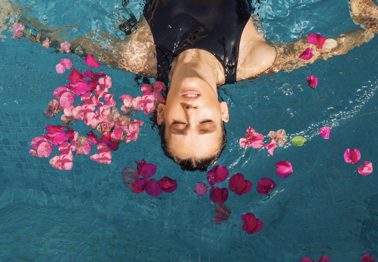 High angle view of woman relaxing on swimming pool full of flowers 