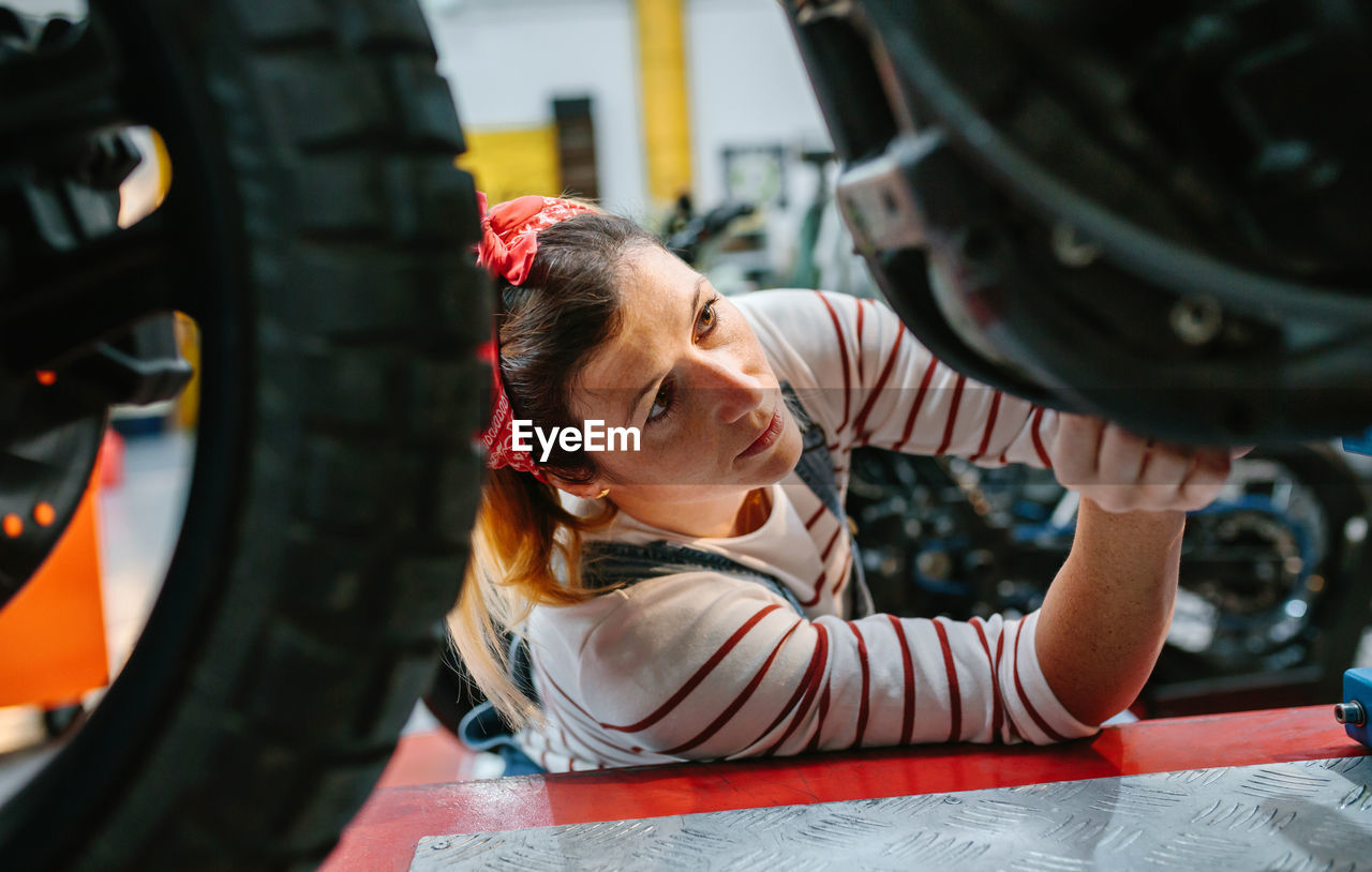 Mechanic woman checking motorcycle on factory