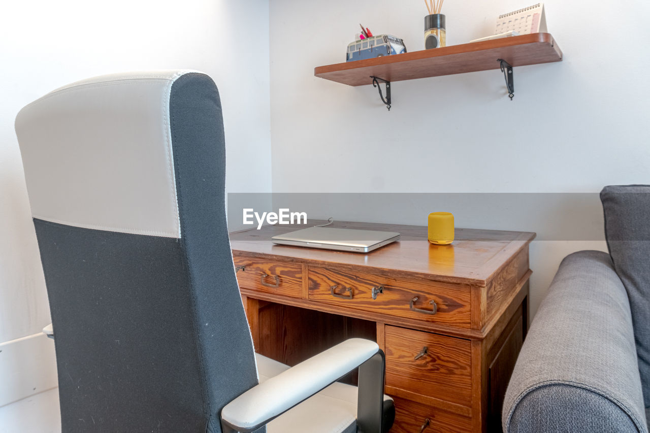 Laptop computer closed on wooden table inside home office in living room interior