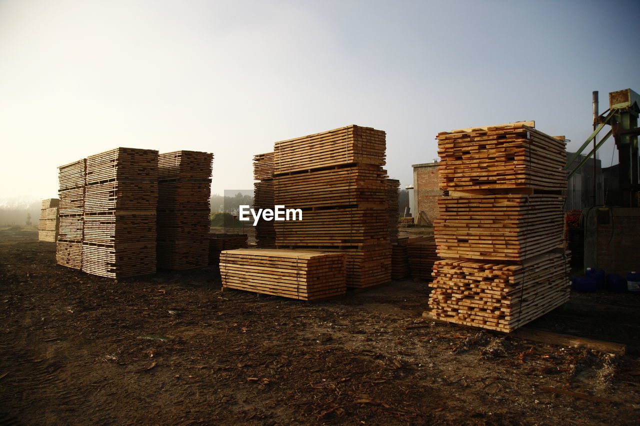 STACK OF FIREWOOD ON FIELD AGAINST SKY