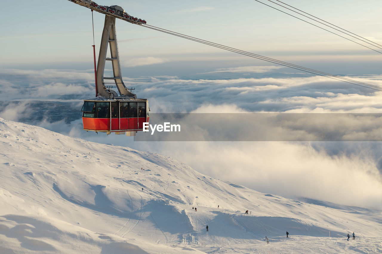 Ski lift above clouds and ski slope