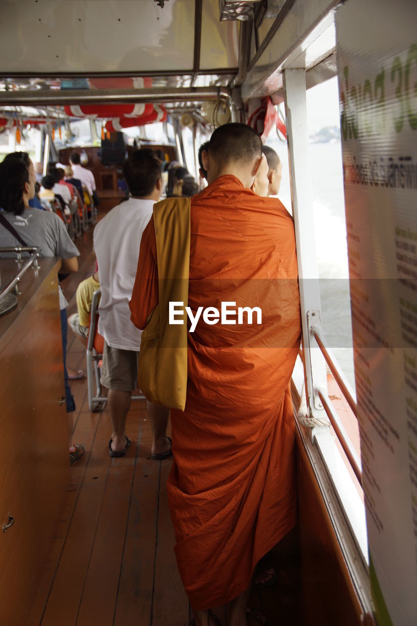 Rear view of monk on boat over lake