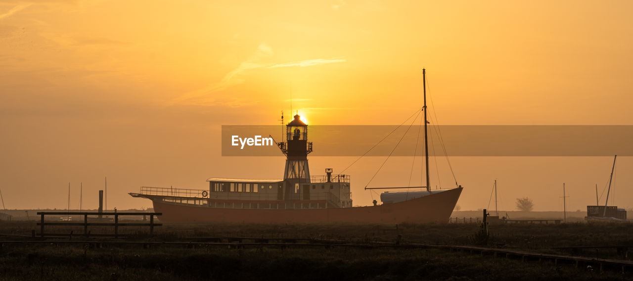 SAILBOAT ON SEA AGAINST ORANGE SKY