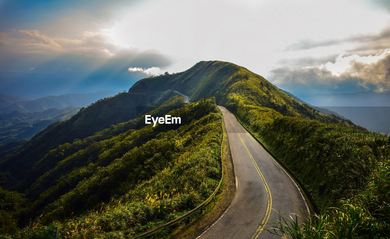 Empty road leading towards mountains against sky