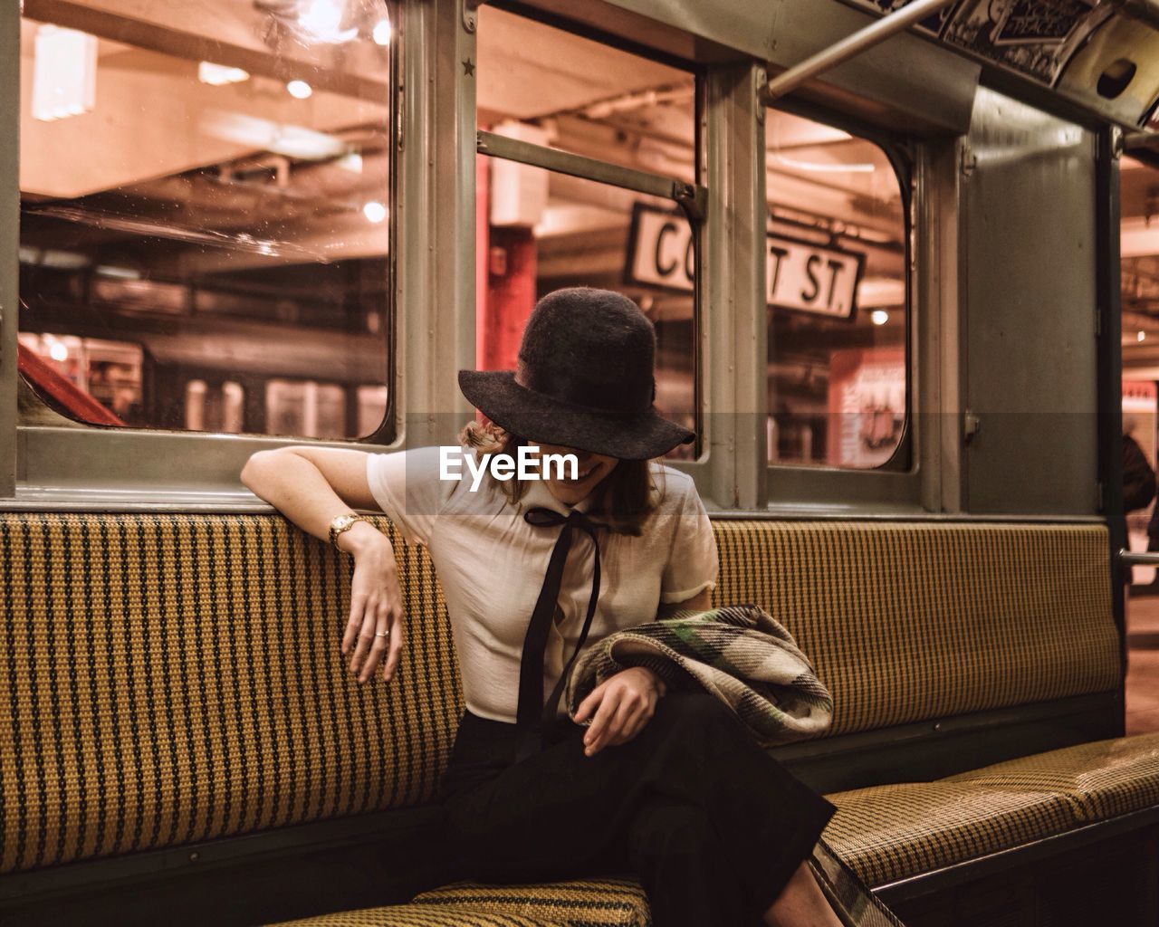 REAR VIEW OF MAN SITTING IN TRAIN AT NIGHT