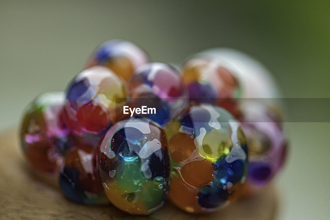 CLOSE-UP OF MULTI COLORED BALLS IN GLASS ON TABLE